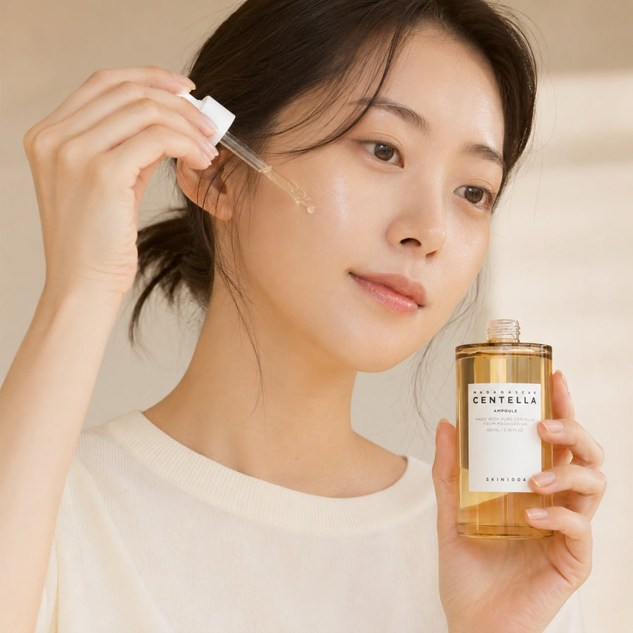 Mujer aplicando la ampolla Centella Ampoule del Kit Calmante SKIN1004 con el gotero sobre la mejilla