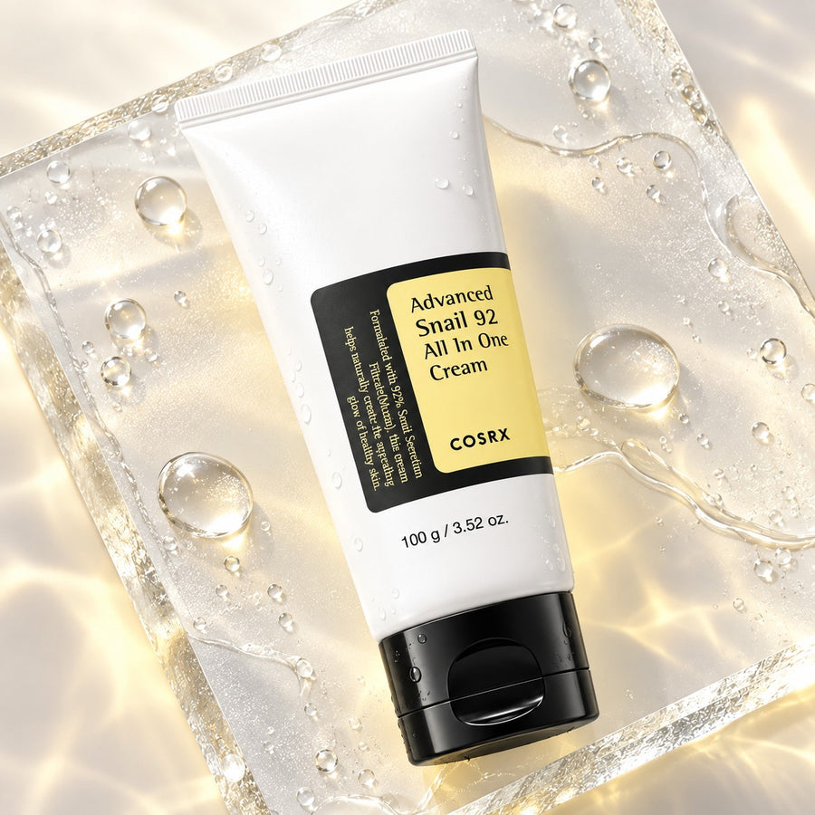 Kit Cuidado Diario COSRX: crema Advanced Snail 92 sobre una superficie de gel con gotas